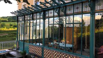 A conservatory with a tiled floor, a table with chairs, and a view of the garden.
