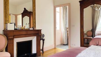 Un dormitorio con chimenea, un espejo grande y una cama con colcha rosa.