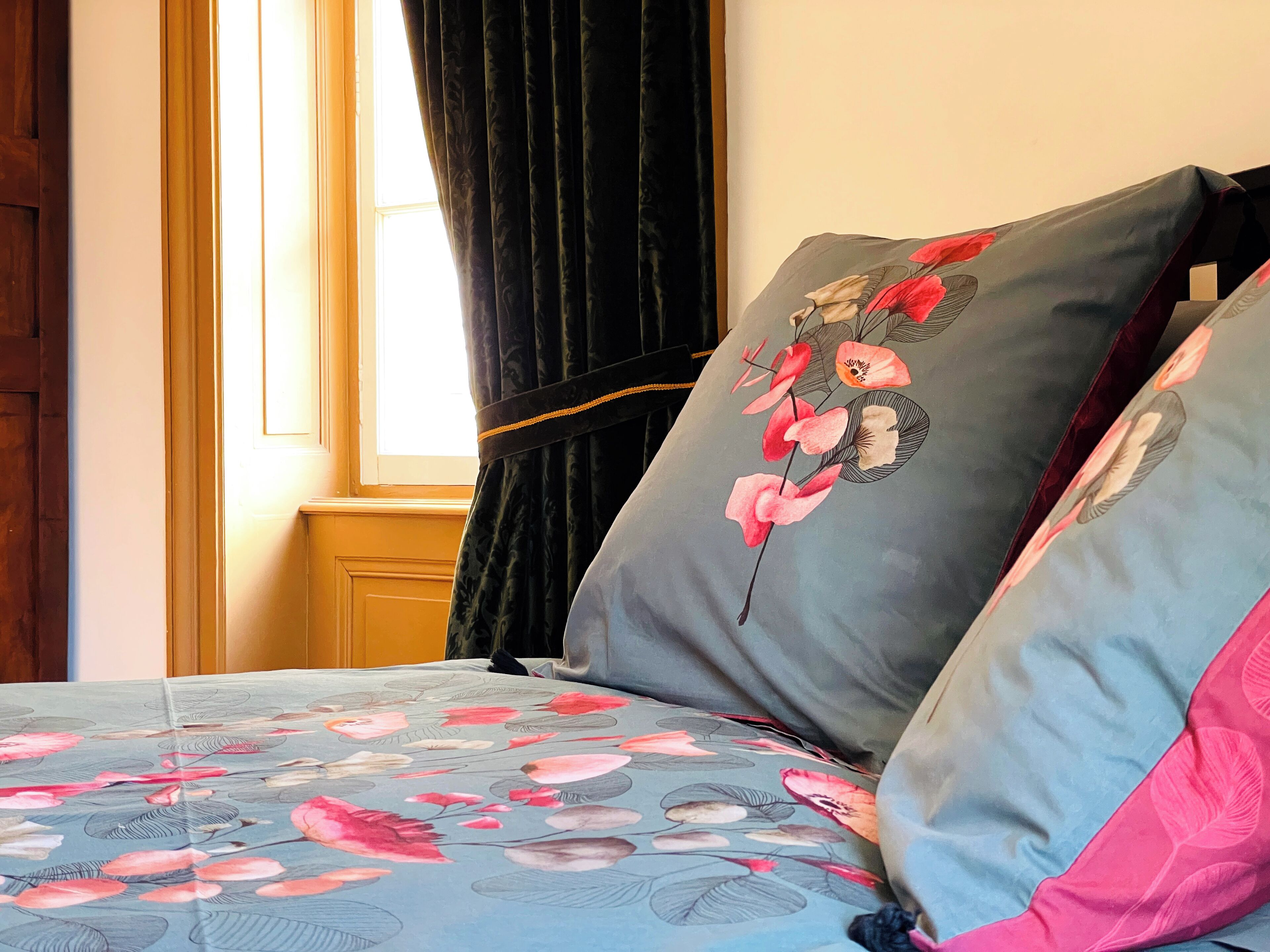 Un lit avec une literie à motifs floraux et deux oreillers ornés de motifs floraux.