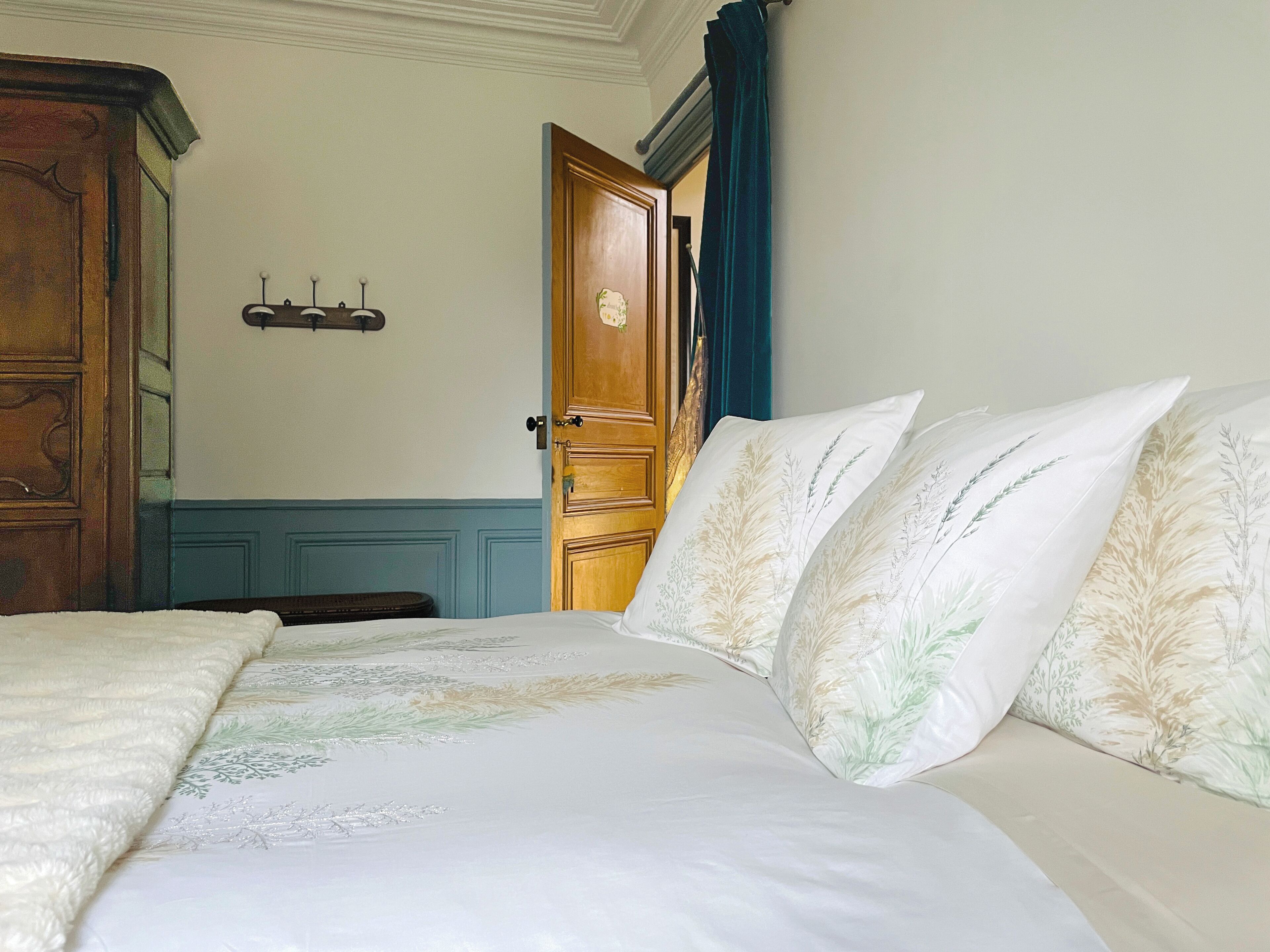 A bedroom with a bed, a wooden wardrobe, and a door with a blue curtain.
