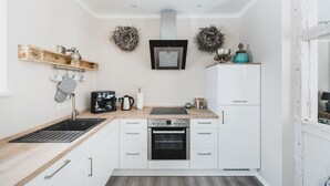 A compact kitchen with white cabinets, a built-in oven, a coffee maker, and a wooden countertop. - Ferienwohnungen Casa Bella Cosa (Braunlage)