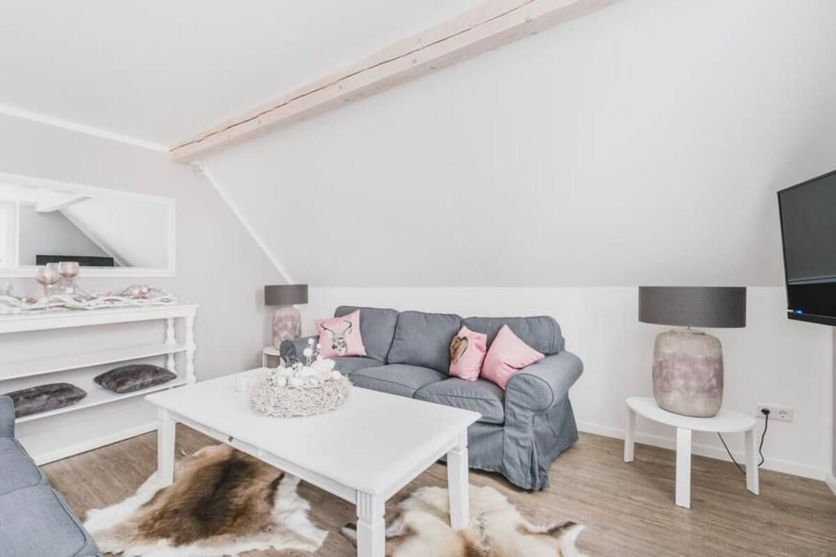 A modern living room with a grey sofa, white coffee table, and a white console table.