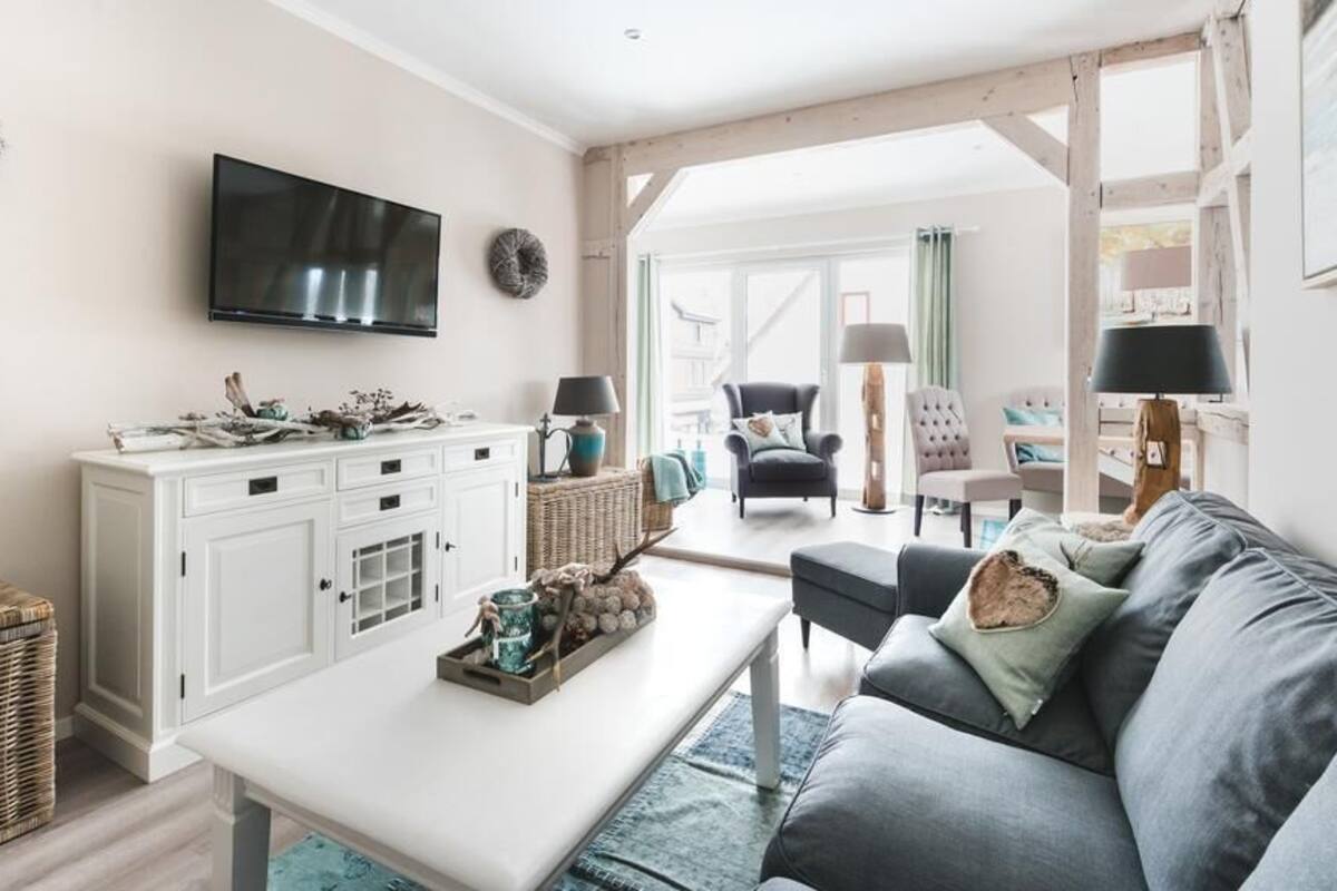 A living room with a white cabinet, a flat-screen TV, a grey sofa, and a coffee table.