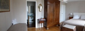 Ein Schlafzimmer mit zwei Betten, einem Holzschrank, einem kleinen Nachttisch und einem Spiegel.