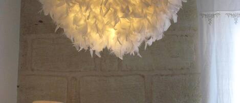 A room with a textured white ceiling fixture, a brick wall, and a white curtain.