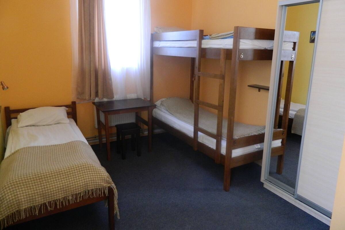 A dormitory room with bunk beds, a desk, and a chair.