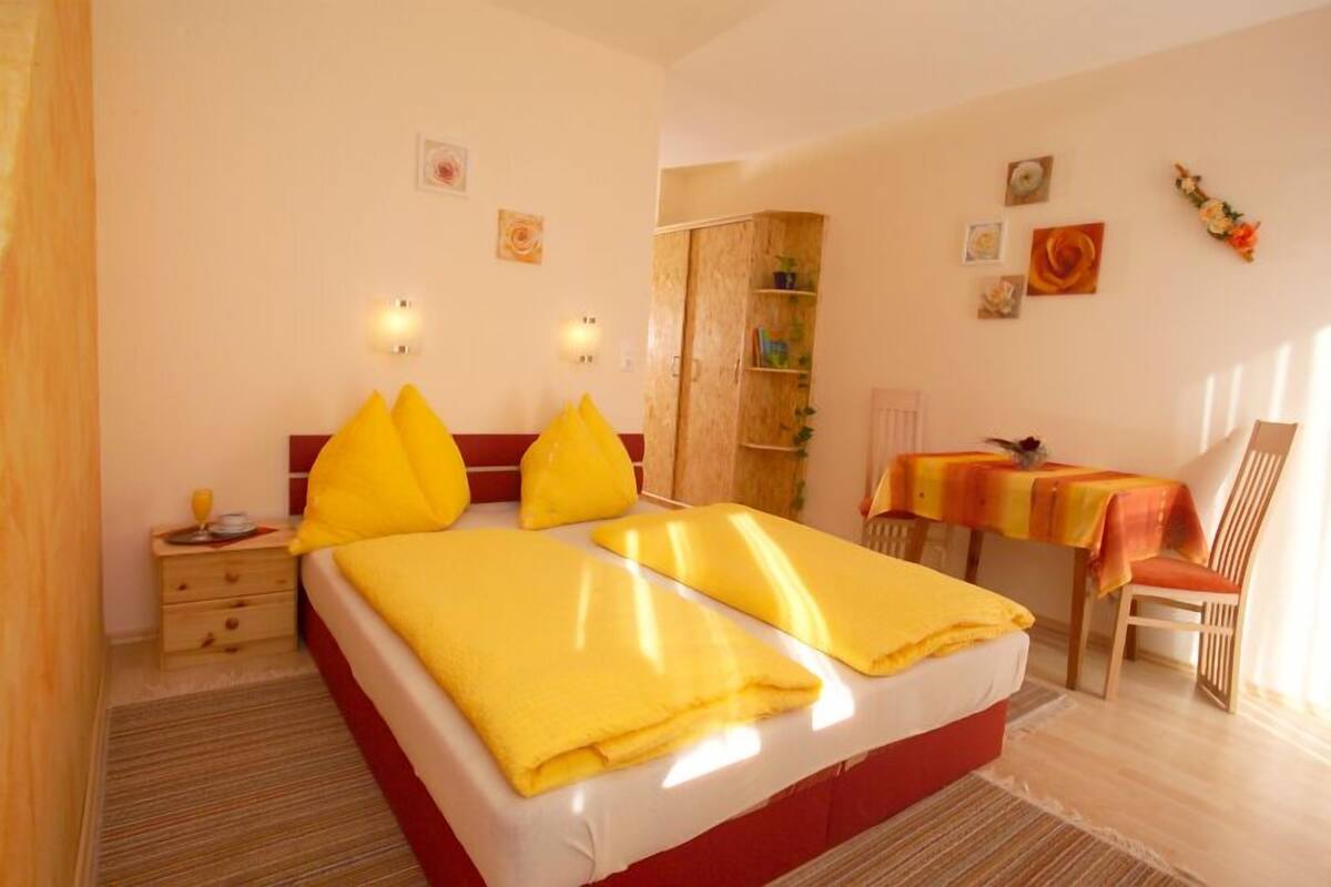 A hotel room with a bed, bedside table, and a small desk with a chair.