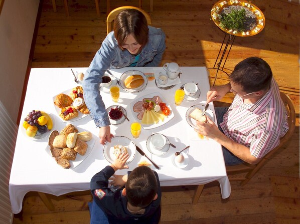 A family dining at a wooden table with a variety of breakfast items.