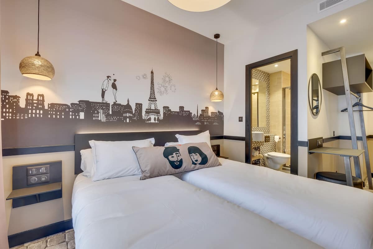Ein Hotelzimmer mit einem Bett, Stadtbild-Wandkunst, einem Spiegel und einem kleinen Tisch.