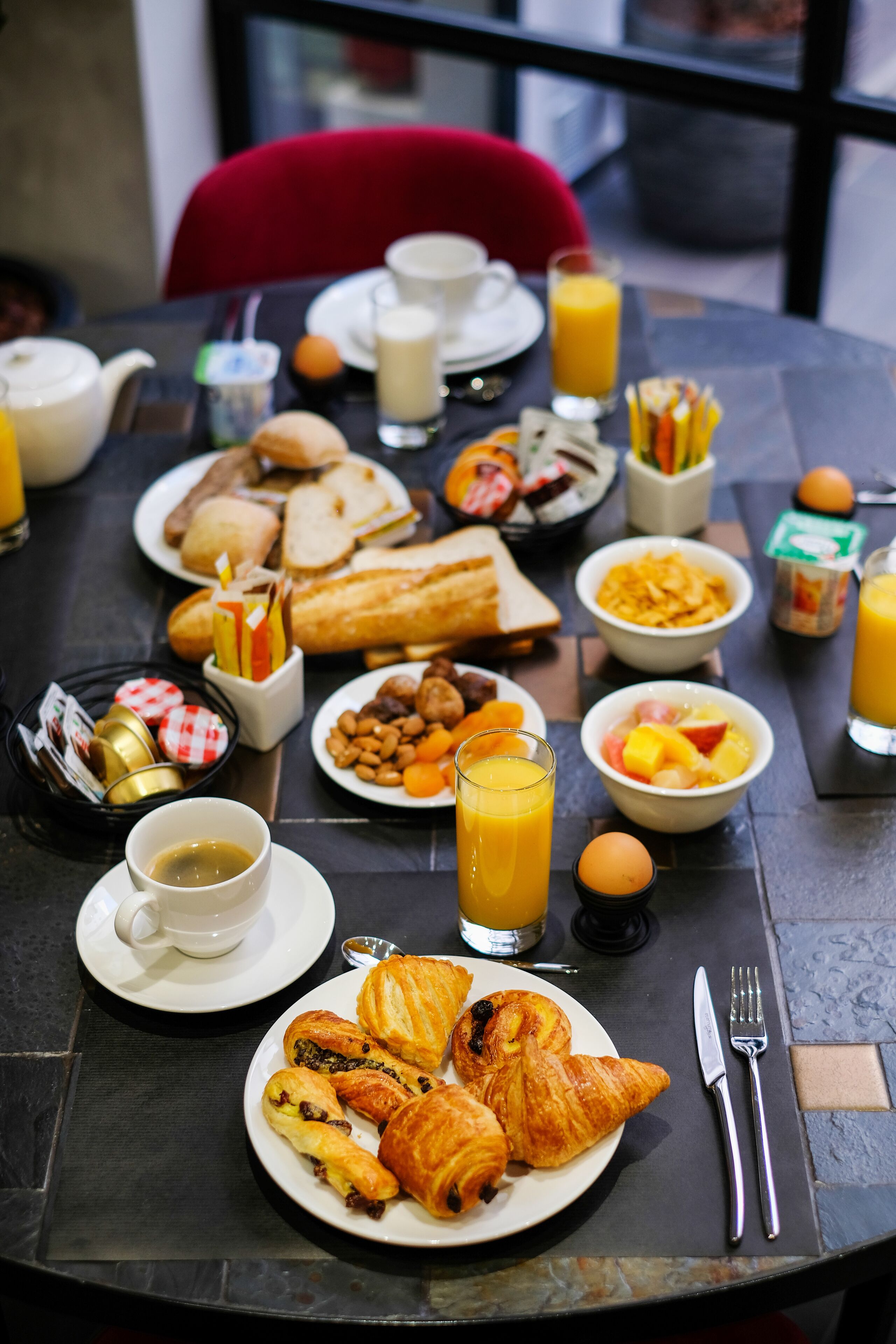 A breakfast table with various food items and drinks.