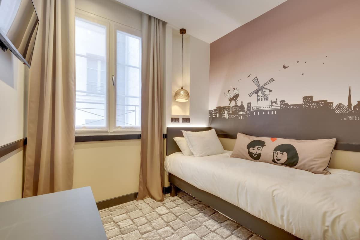 Ein Hotelzimmer mit Bett, einem Stadt-Wandbild, einem Fenster mit Vorhängen und einer Hängeleuchte.