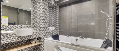 Un baño moderno con una bañera grande, un espejo y una zona de ducha.