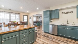 A kitchen with teal cabinets, a wooden countertop, and a stainless steel dishwasher. - Central Atlanta 8BR and 3600 sqft (Atlanta)