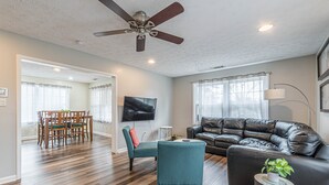 A modern living room with a leather sofa, teal armchairs, and a dining area with wooden chairs and a table. - Central Atlanta 8BR and 3600 sqft (Atlanta)