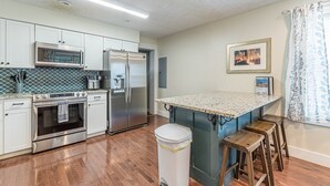 A modern kitchen with stainless steel appliances, a granite countertop, and wooden stools. - Central Atlanta 8BR and 3600 sqft (Atlanta)