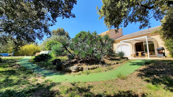 A house with a covered patio, a lawn, and a variety of plants.