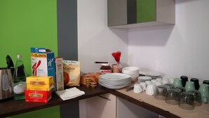 A kitchen counter with various food items, kitchenware, and a green wall. - Dimora dell'Arte B&B (Sesto San Giovanni)