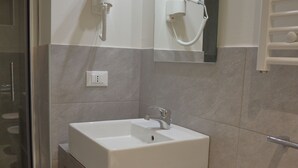 A modern bathroom with a white sink, a mirror, and a hairdryer on the wall. - Dimora dell'Arte B&B (Sesto San Giovanni)