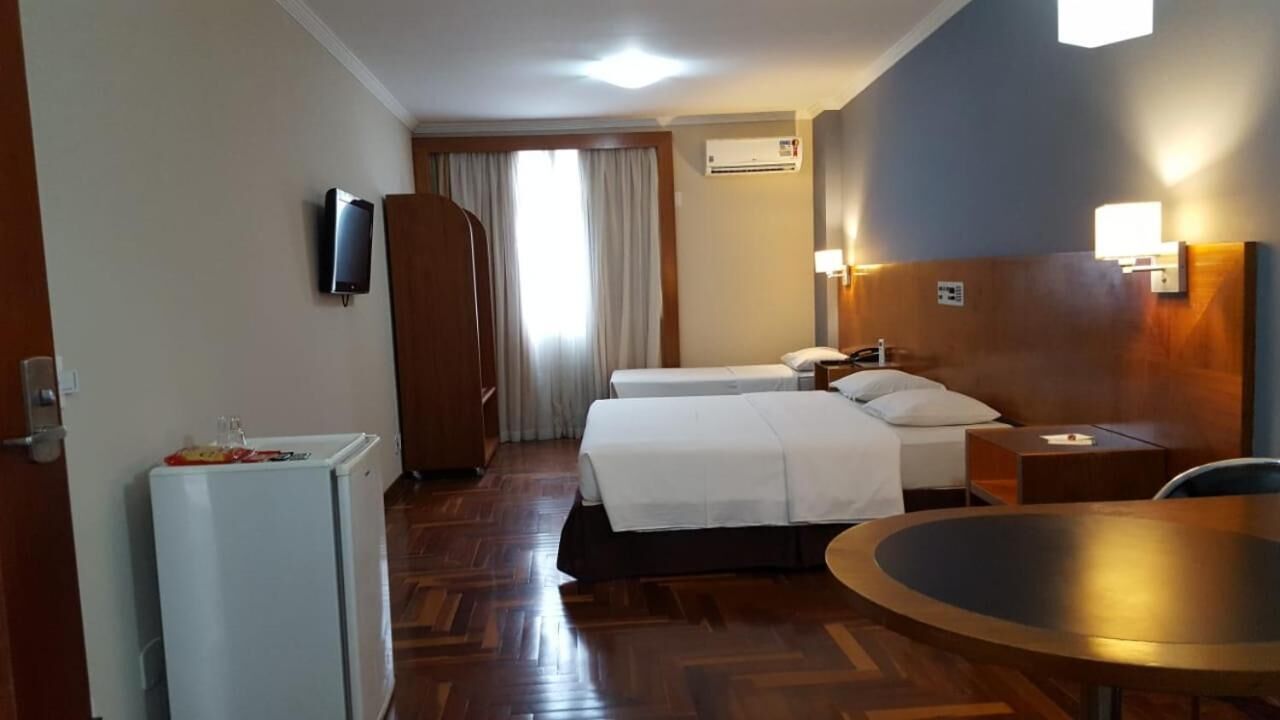 Une chambre d’hôtel avec deux lits, un bureau, une chaise, un téléviseur et un appareil de climatisation.
