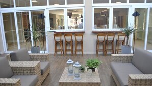 Eine Lobby mit Korbmöbeln, einem zentralen Couchtisch und Topfpflanzen.