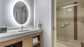 Un baño moderno con un espejo grande, dos lavamanos, una cabina de ducha de vidrio y un perchero para toallas.