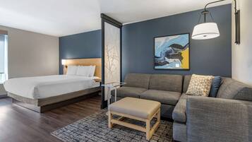 Una habitación de hotel moderna con cama, sofá y una pequeña mesa.