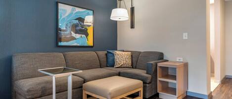 Una sala de estar moderna con un sofá modular, una mesita, un banco, una lámpara de pared y una estantería.