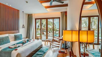 A hotel room with a bed, a desk, a chair, a lamp, and a view of a pool and palm trees.