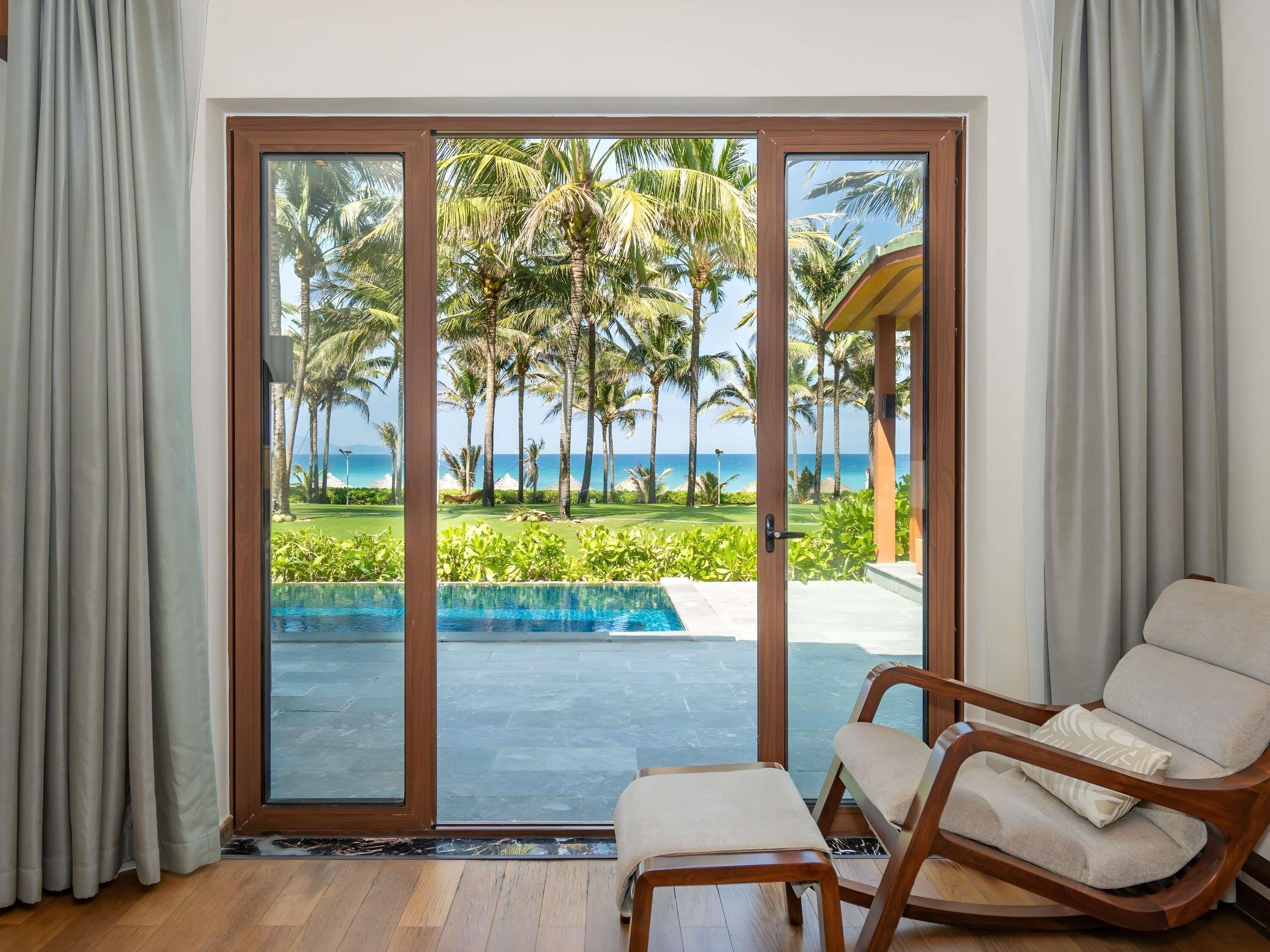 A room with a sliding glass door leading to a pool and a beach view.