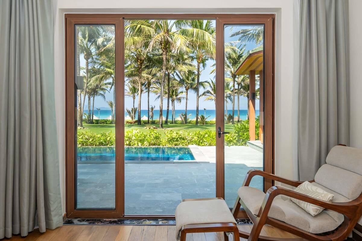 Una habitación con puerta corrediza de vidrio que da a una piscina y vista al mar.