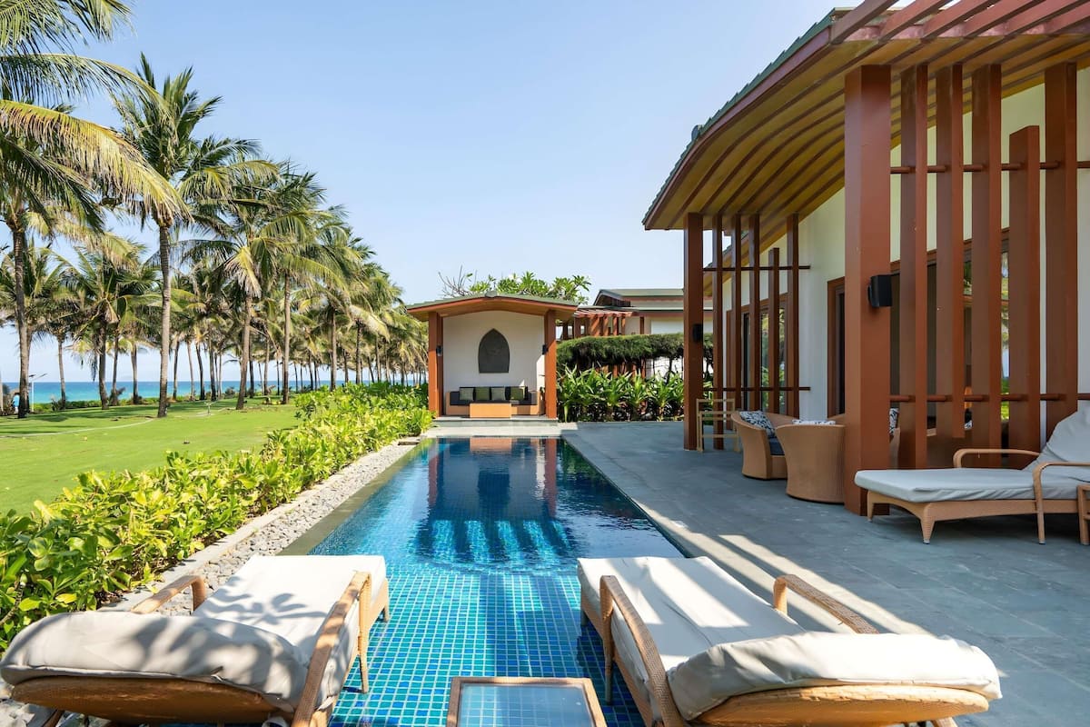 A poolside area with lounge chairs, a small seating area, and a view of the ocean.
