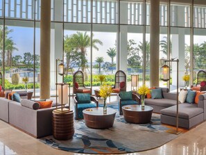 A spacious lobby with large windows, comfortable seating, and a view of a pool and greenery.