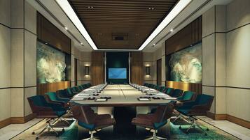 A conference room with a long table, multiple chairs, and a large screen at the front.