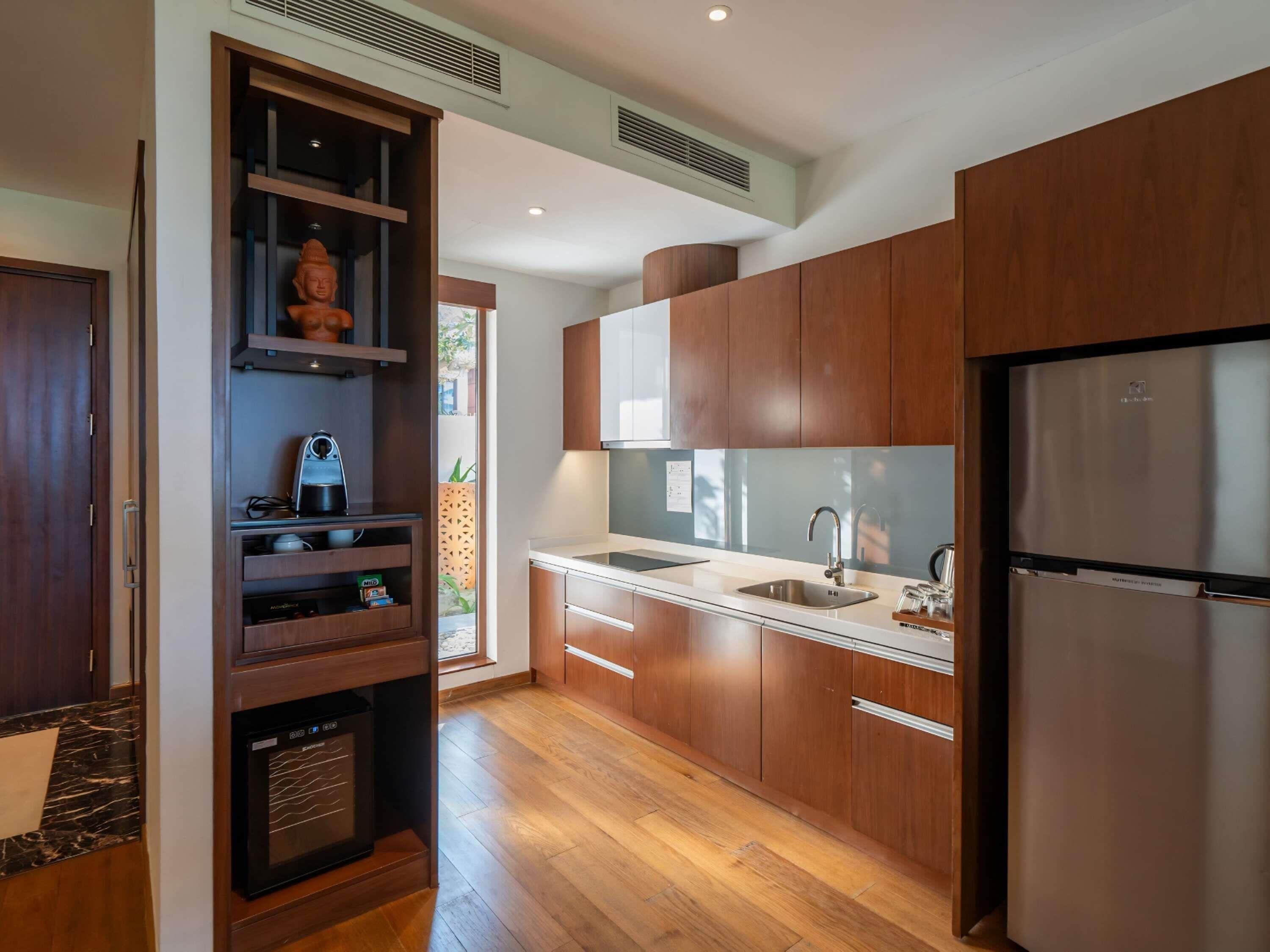 A modern kitchen with wooden cabinets, a stainless steel refrigerator, and a built-in oven.