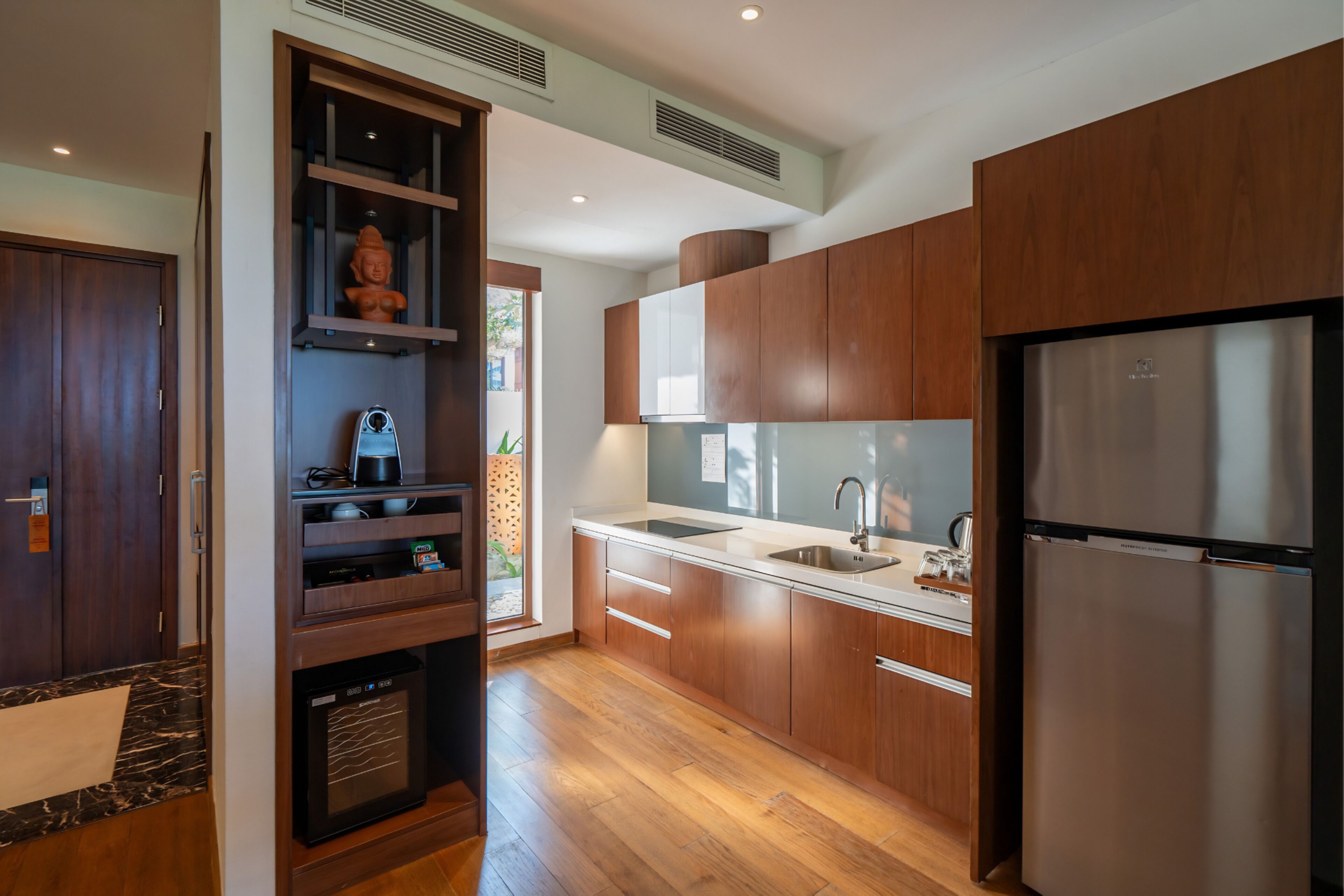 A modern kitchen with wooden cabinets, a stainless steel refrigerator, and a built-in oven.