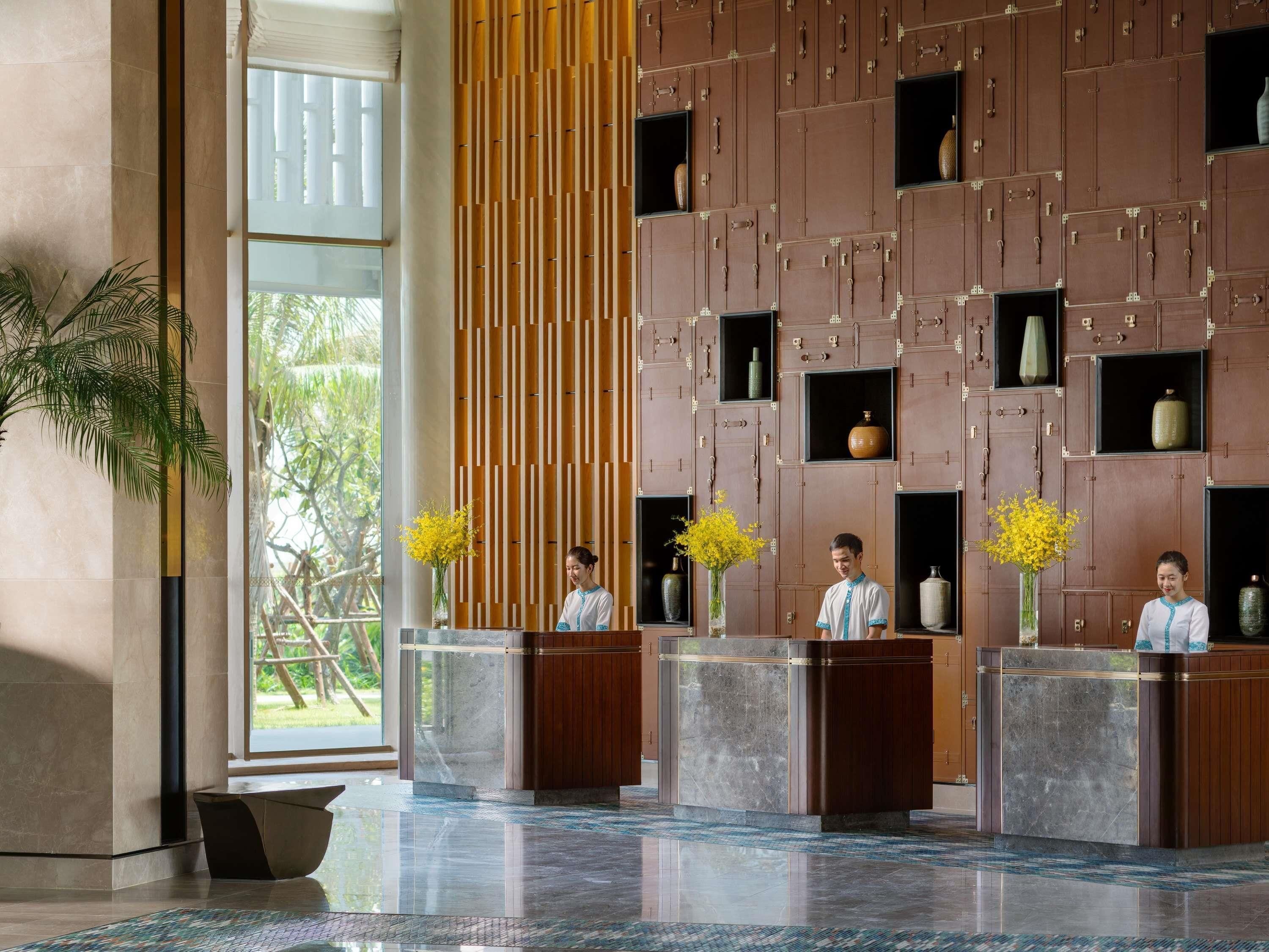 Een receptiegedeelte met een modern design, met een receptiebalie, verticale houten panelen en decoratieve vazen.