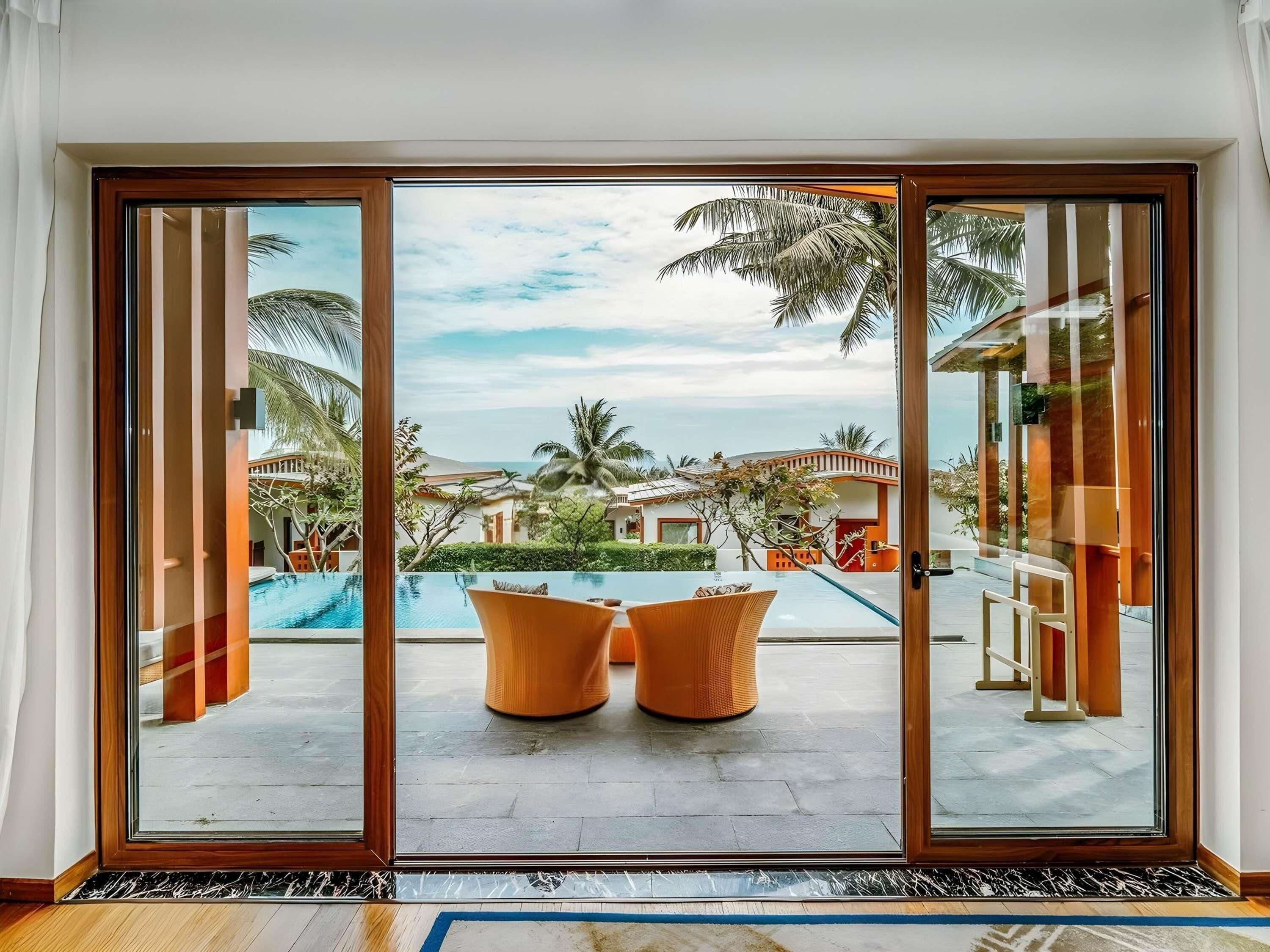 A room with a large sliding glass door leading to a pool area with two chairs.