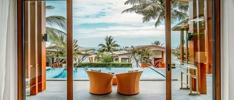A room with a large sliding glass door leading to a pool area with two chairs.