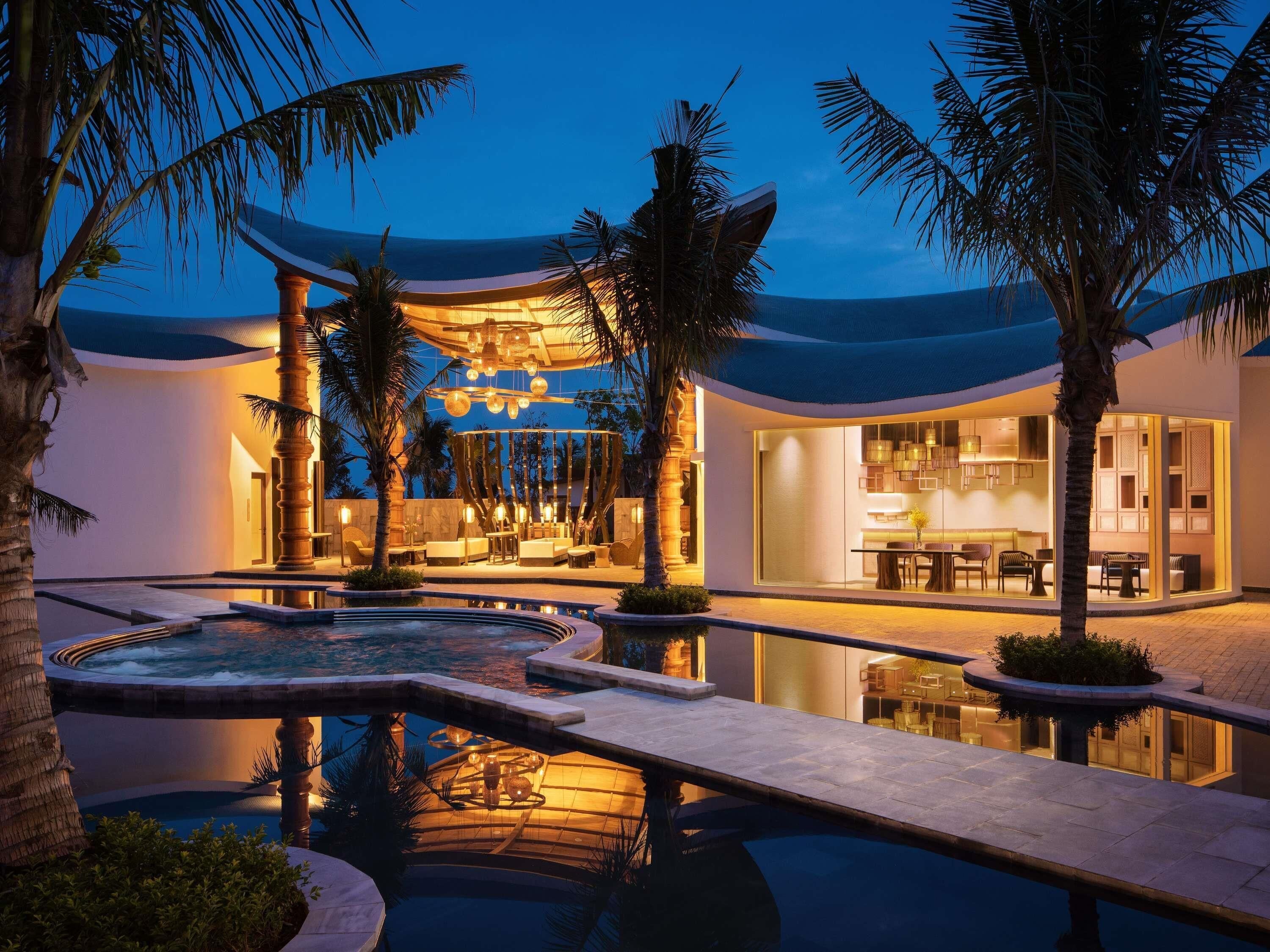 A modern resort with a pool, lounge area, and a well-lit interior.
