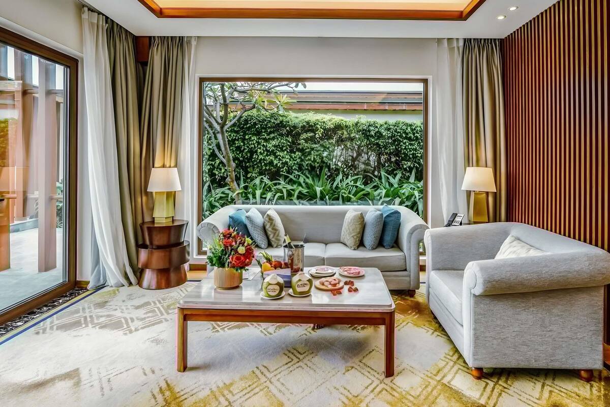 A modern living room with a sofa, armchair, coffee table, and lamps.