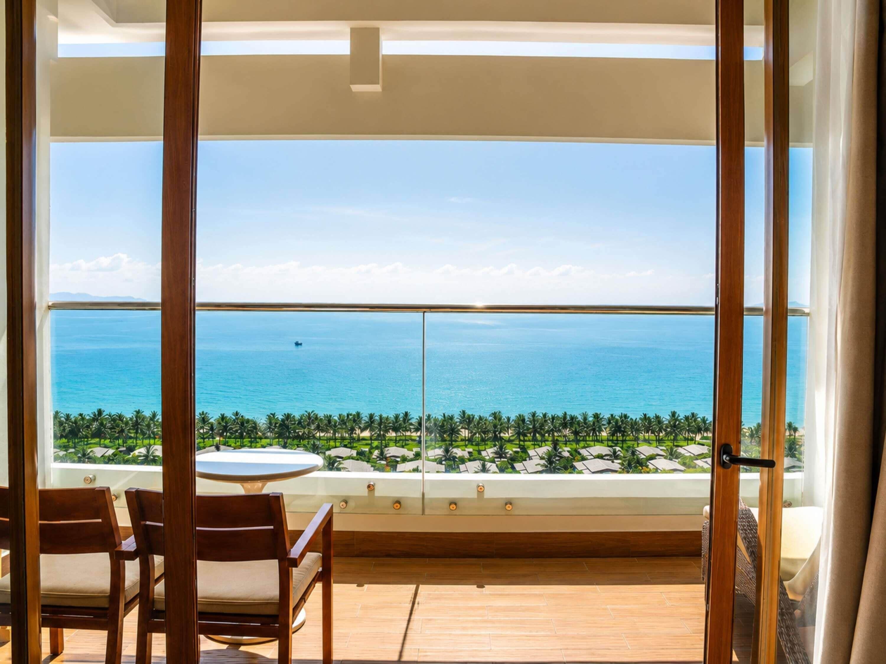 A balcony with a view of the ocean and palm trees.