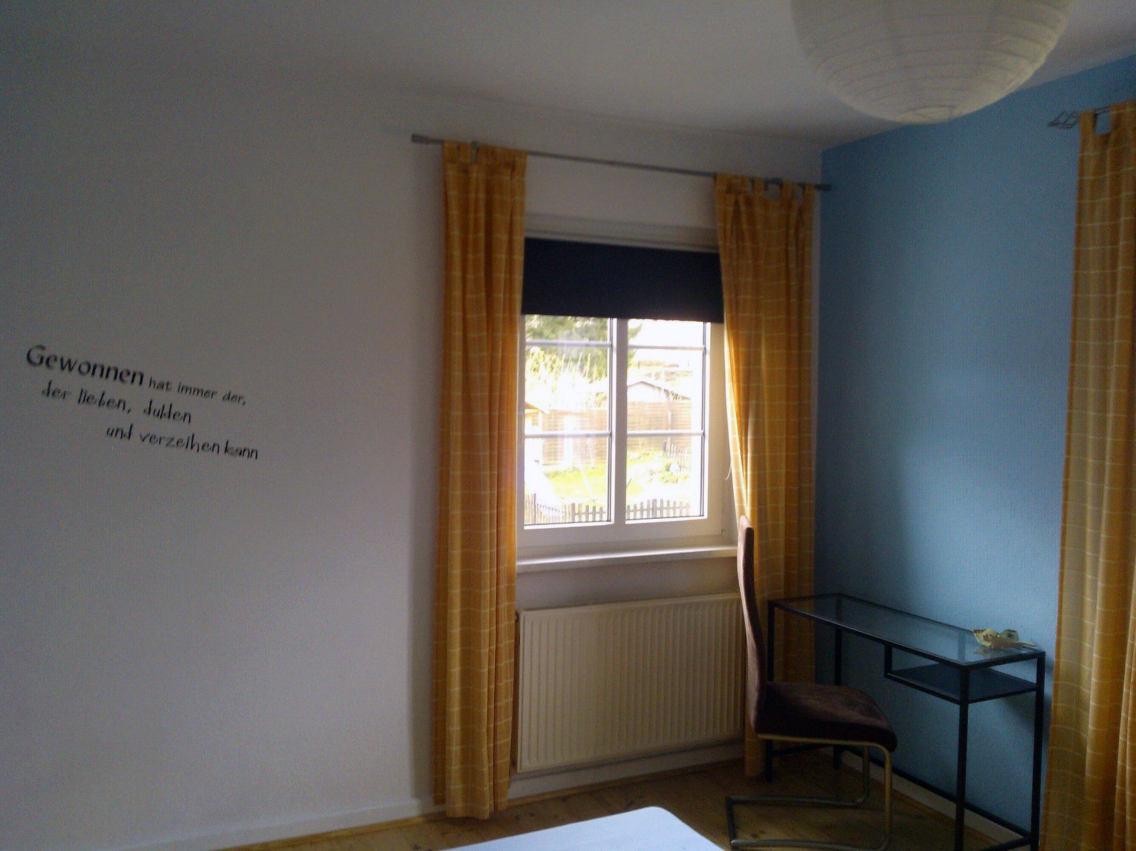 Ein Zimmer mit Fenster, Heizkörper, Stuhl und Tisch.