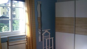 A bedroom with two beds, a radiator, a window with curtains, and a wardrobe. - Ferienhaus XXL Deutschland (Schwarzatal)