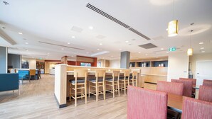Un restaurant moderne avec des tables et des chaises en bois, un comptoir et un sol carrelé et impeccable.