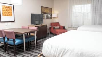 A hotel room with a bed, a desk with a chair, a television, and artwork on the wall.