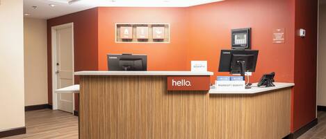 Un mostrador de recepción con un cartel que dice 'hello', una computadora Lenovo, un teléfono y un cartel de Marriott Bonvoy.