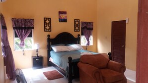 Una camera da letto con un letto, un comodino, una sedia e una porta.