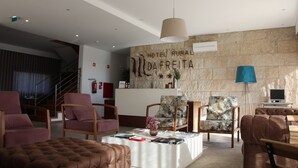 A modern hotel lobby with a stone wall, a reception desk, and comfortable seating areas. - Hotel Rural da Freita (Arouca)