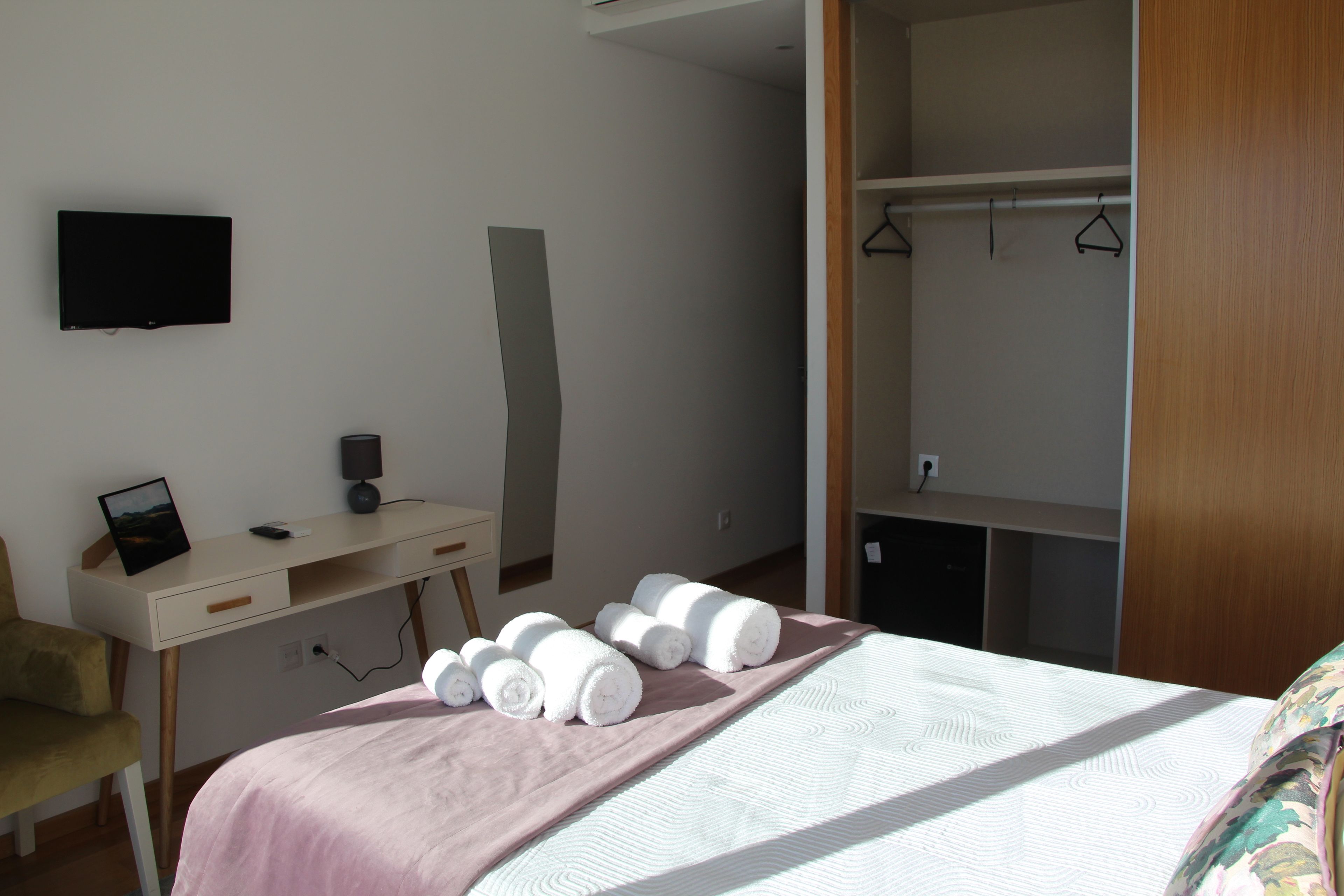 A bedroom with a bed, a desk, a chair, a TV, and a wardrobe.