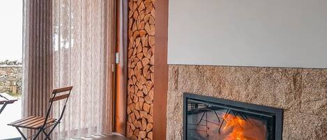 A modern living room with a fireplace, a stone wall, and a wooden bench.